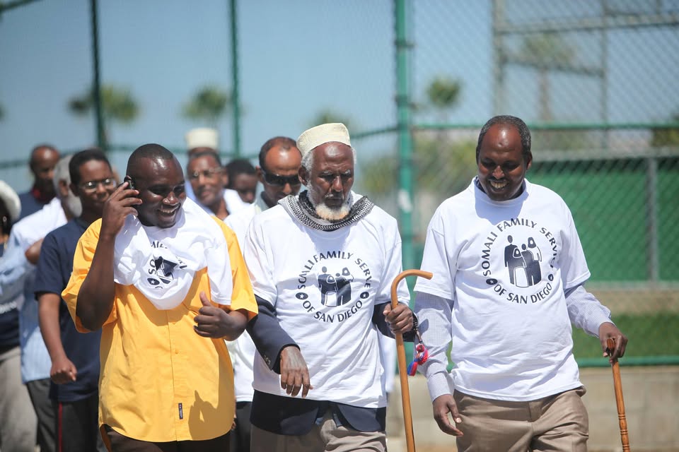 Group of men walking with Somali Family Service of San Diego shirts on
