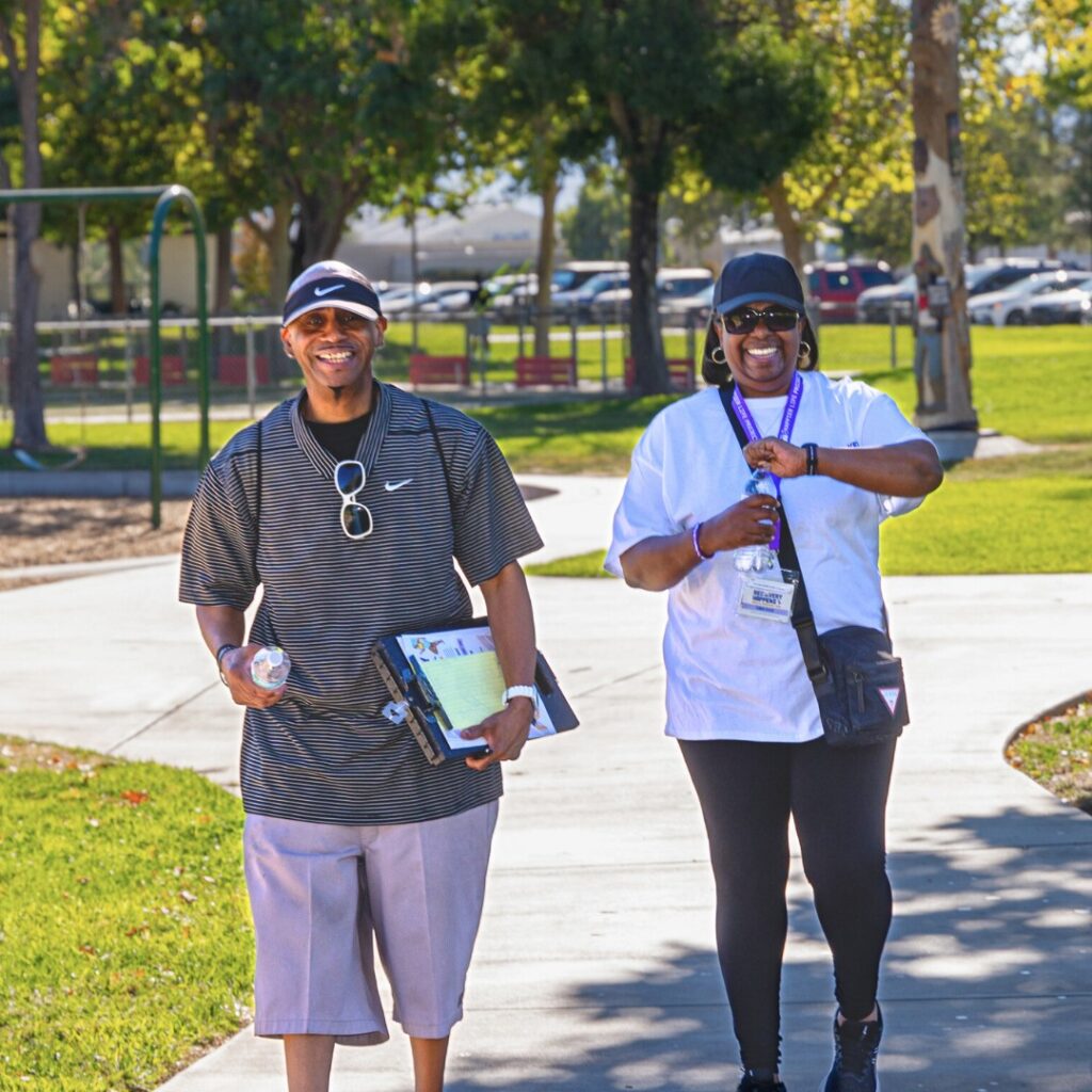 Two people from The Happier Life Project smiling and walking through the park