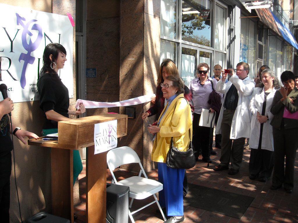 Group of people smiling at woman on Lyon‑Martin Community Health Services podium