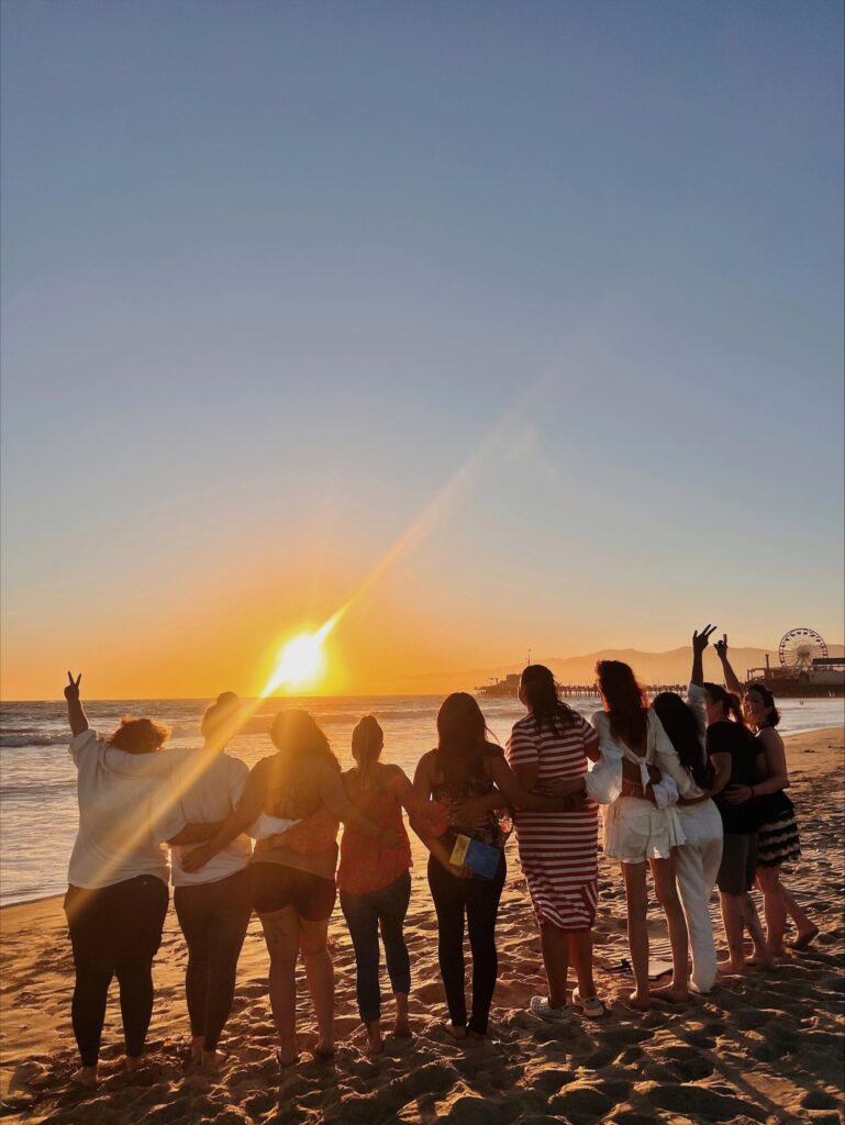 Group of people standing together on the beech watching the sunset