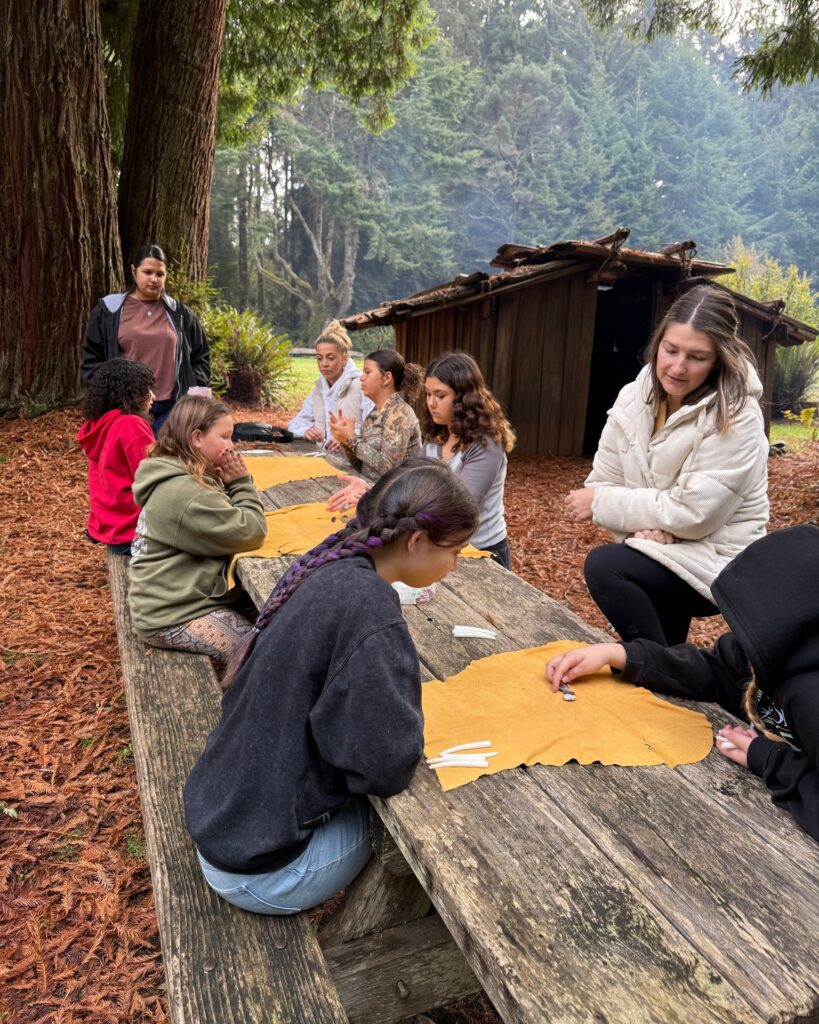 Kids sitting at table in the woods doing a traditional activity