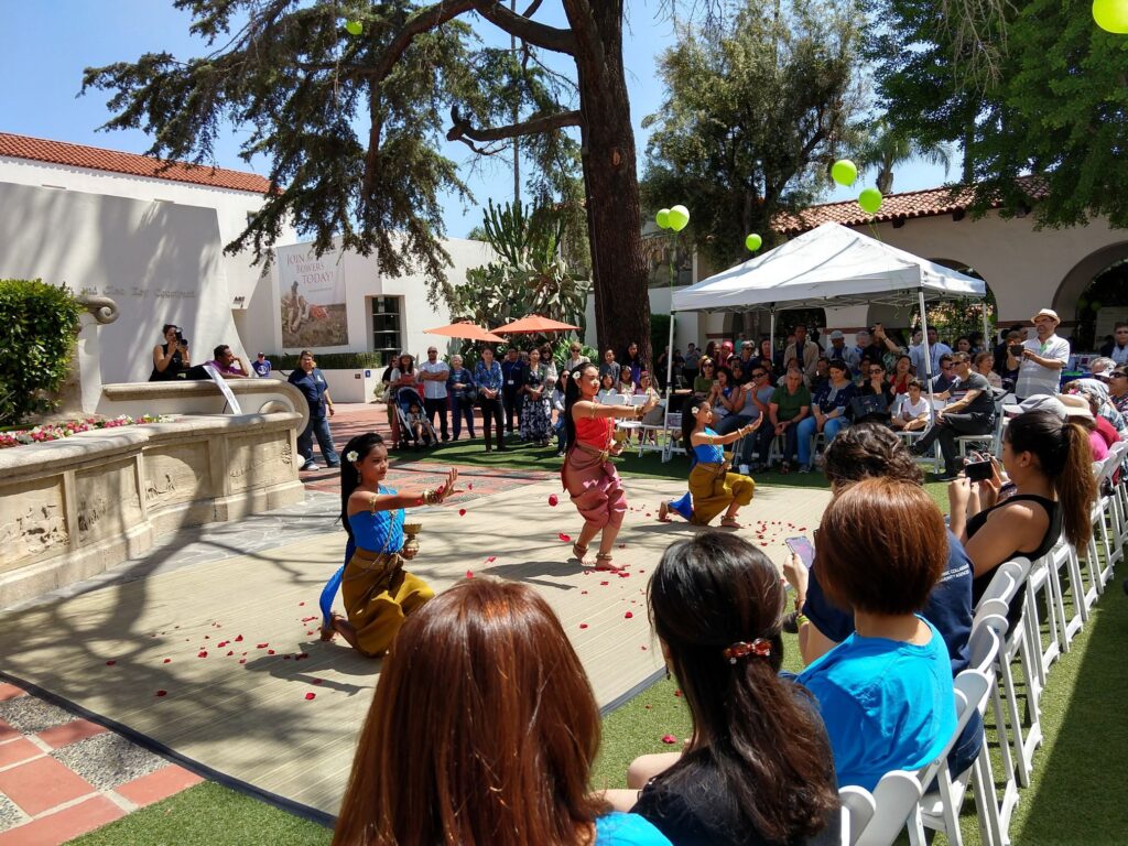 Three women doing cultural dance in front of crowd