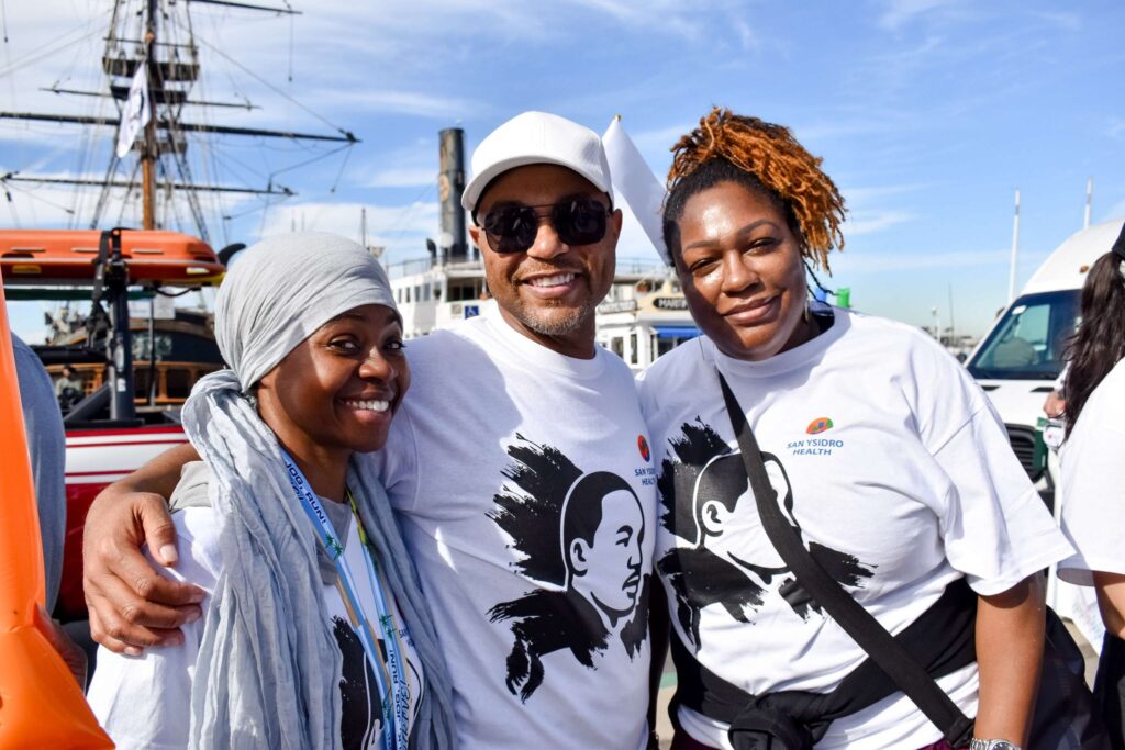 Three people smiling and wearing San Ysidro Health shirts