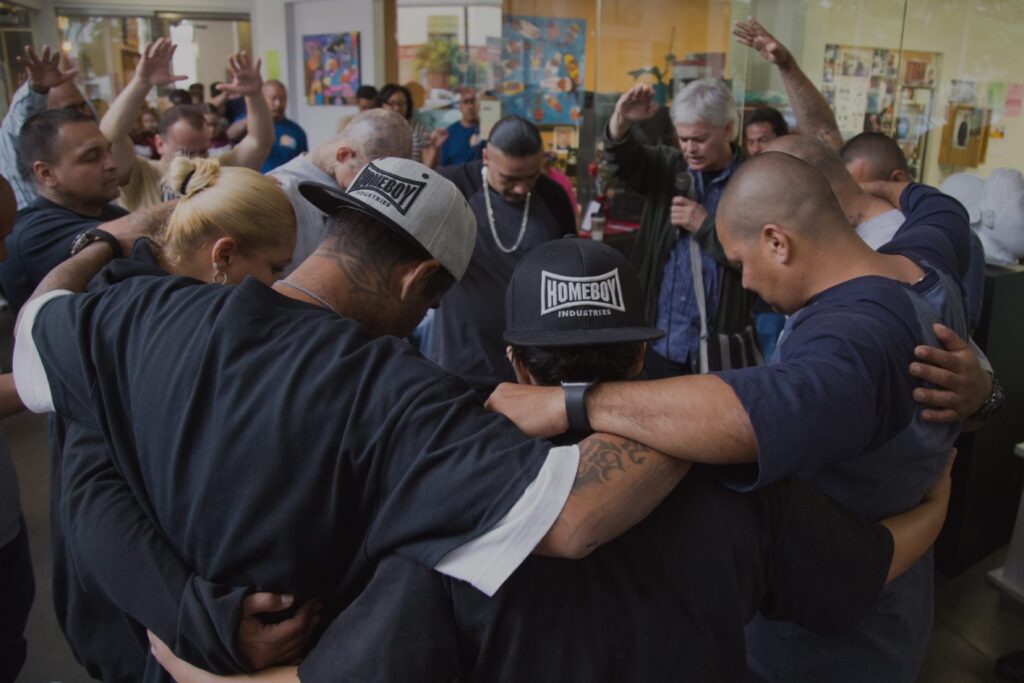 Group of people with linked arms praying in a circle
