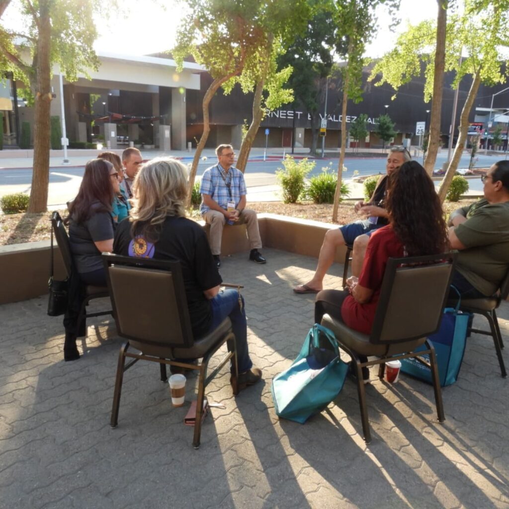 Group of people sitting in a circle outside having a discussion