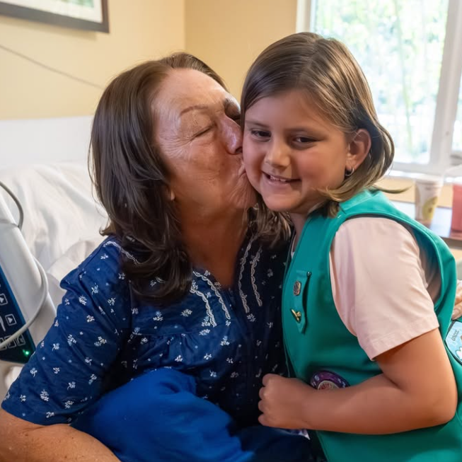 Grandmother in hospital kissing granddaughter on the cheek