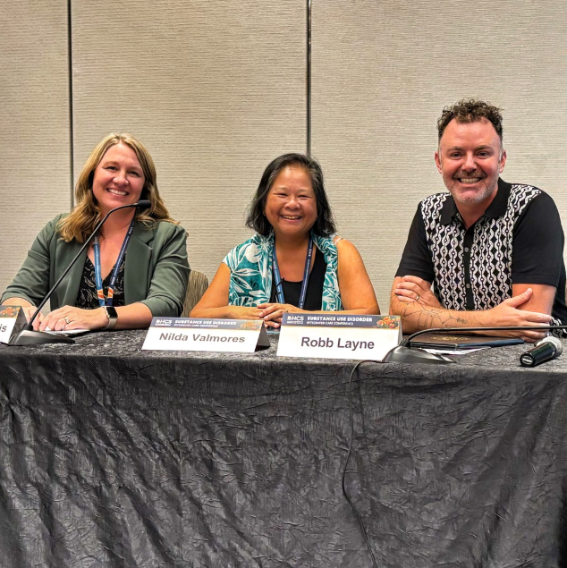 A man and two women smiling while sitting at booth for California Association of Alcohol and Drug Program Executives