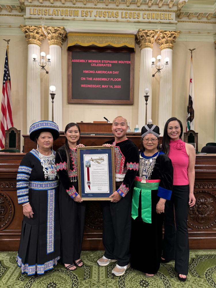 People from Hmong Innovating Politics on the assembly floor holding a resolution document
