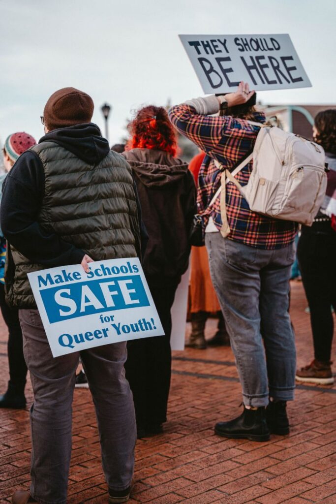People in somber mood holding signs at a vigil